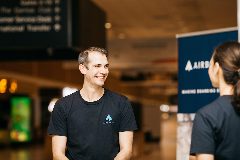 photo of a man in a airboard tshirt looking at a woman with an airboard sign in the background